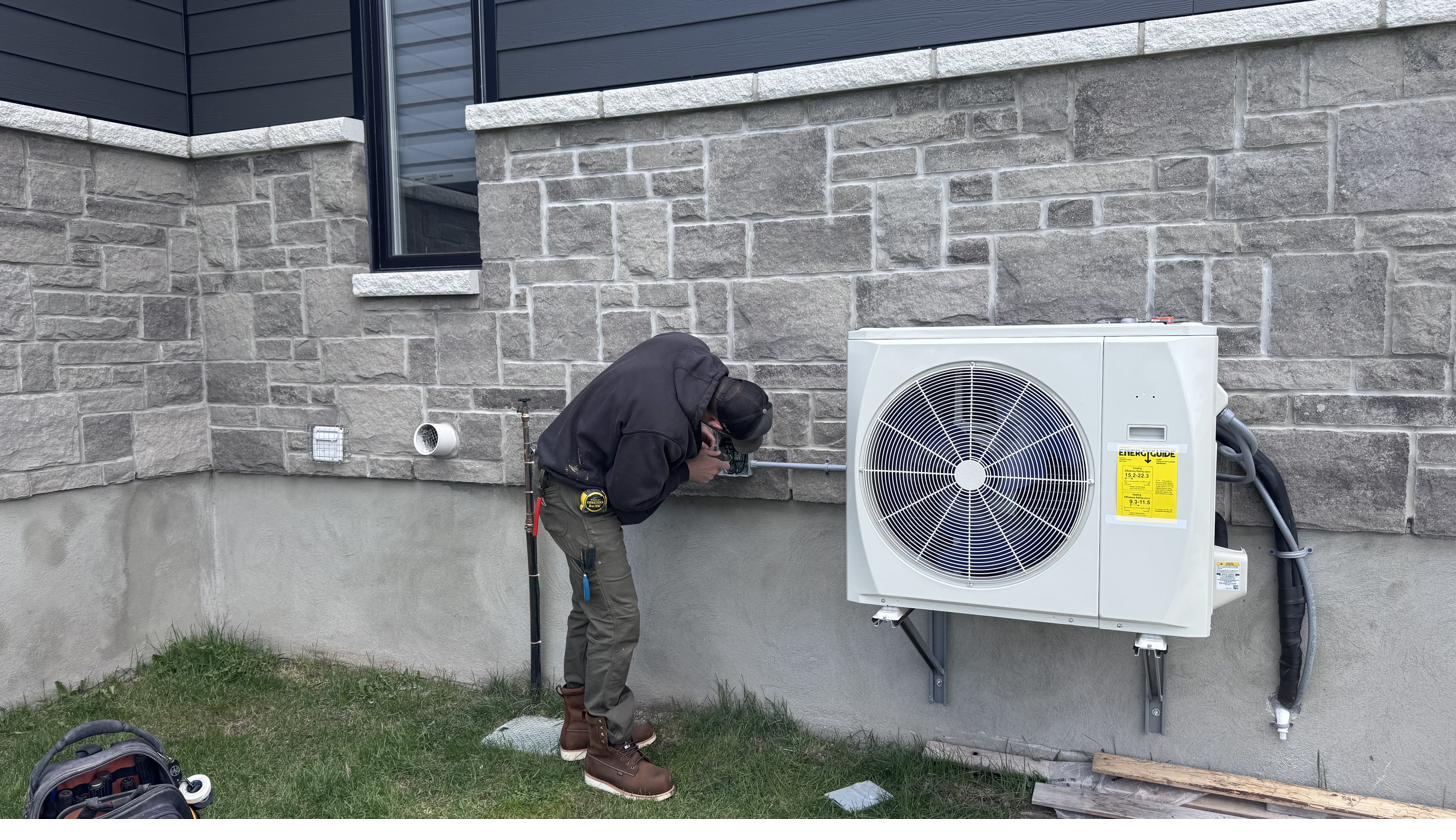 Electrician wiring the disconnect for a residential heat pump installation in Ottawa